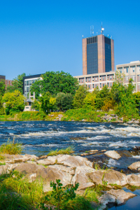Campus buildings across the Rideau River on a sunny day.