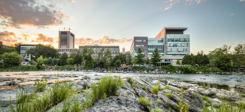 A photo of campus taken across the river at sunset.