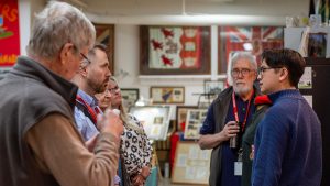 Jacky Chan standing at the Scouts Canada National Museum, speaking with other individuals.