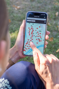 Hands hold an iPhone displaying the Carleton Mobile campus map.