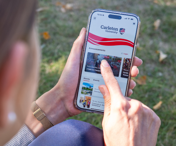 Hands hold an iPhone displaying the Carleton Mobile app home screen.