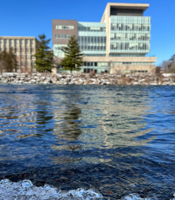 Richcraft Hall across the Rideau River. Ice along the river's edge is in focus at the bottom of the photo.