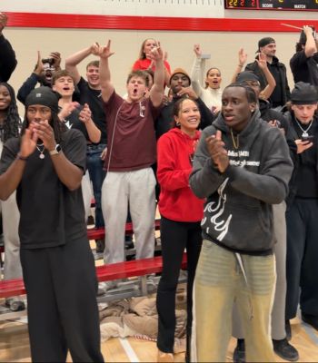 A group of students cheering and clapping during a sports game.
