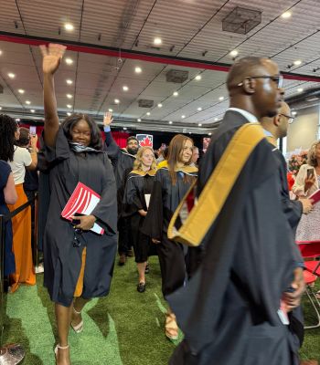 Students in graduation gowns walking and cheering at Carleton University Convocation ceremony.
