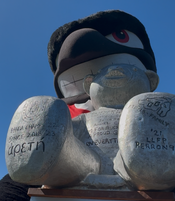 Rodney the Raven mascot holding Pedro the Panda trophy.